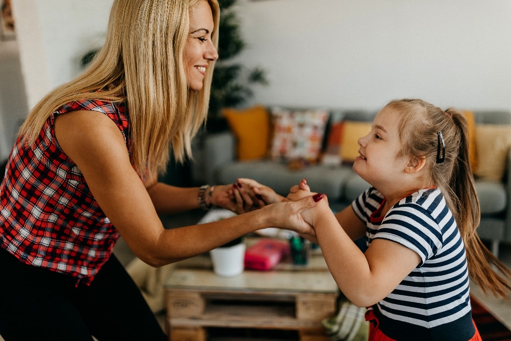 A mother dancing with her young daughter in the living room